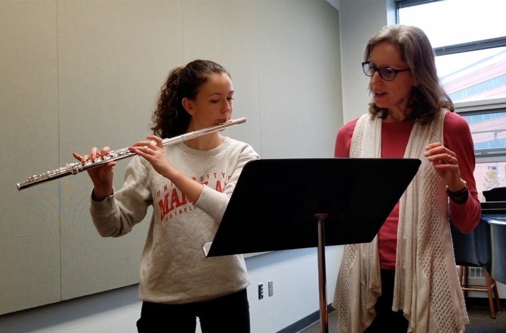 Melissa teaches a private flute lesson to a high school student